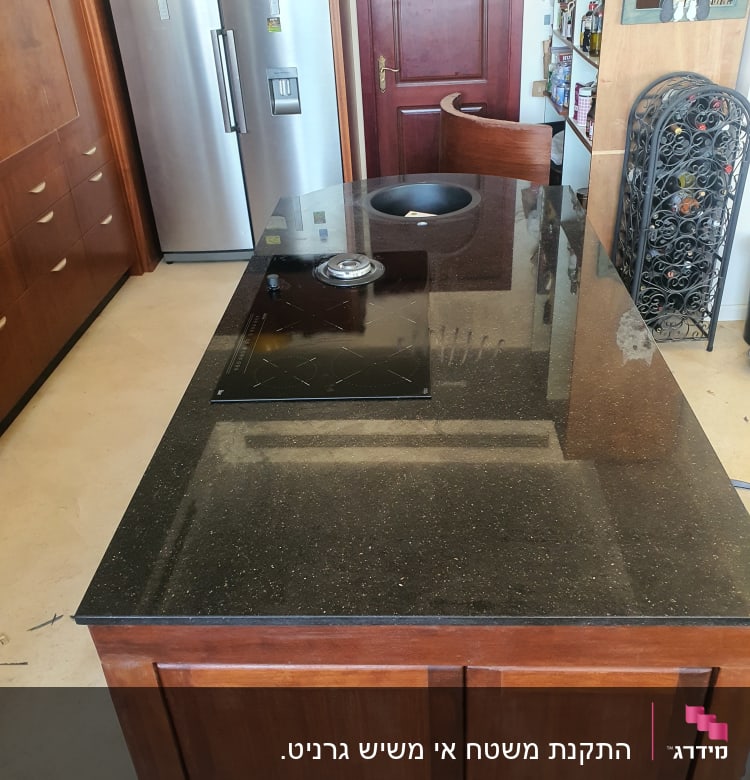 משטח שיש שחור עם כיור וכיריים במטבח